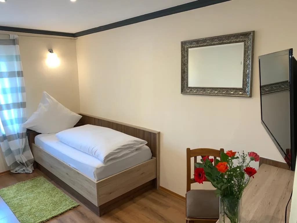 Gemütliches Zimmer mit Bett, Fernseher und Frischblumen