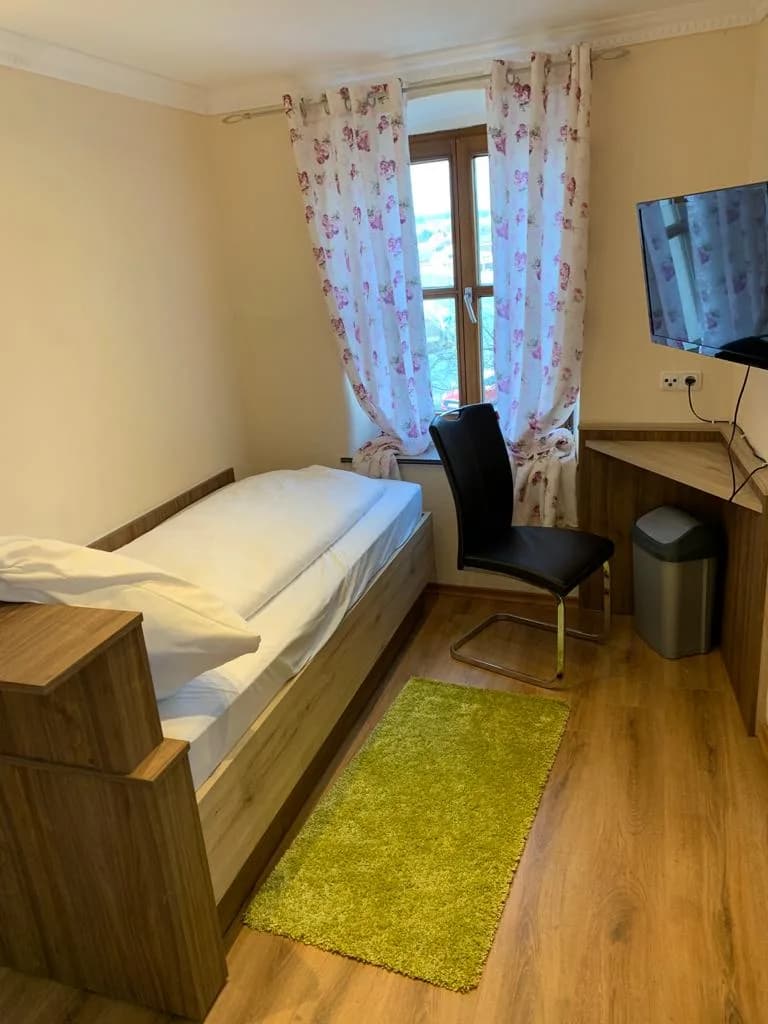 Zimmer mit Bett, Sessel und Fenster zum Hof
